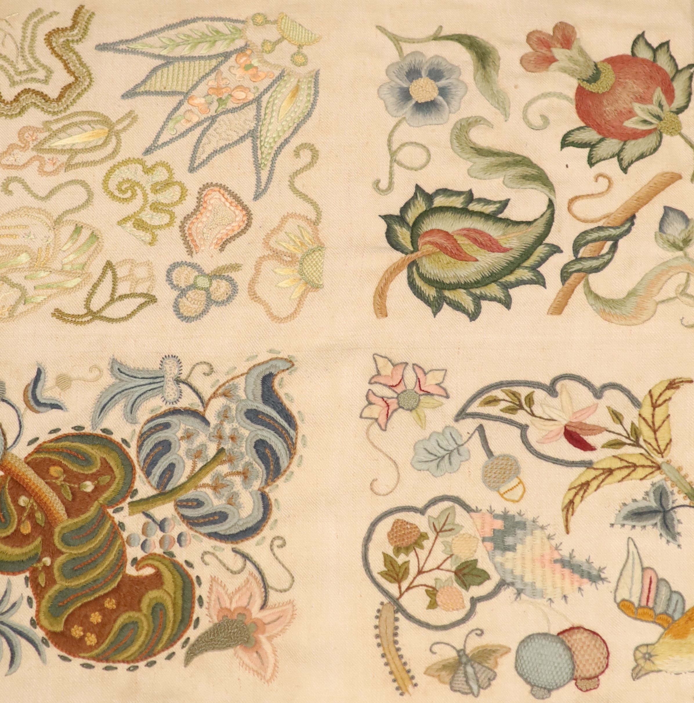 Two crewel work panels, one depicting fruits and flowers, the other quartered with foliage, 50 x 46cm, in simulated mahogany frames, overall 69 x 65cm